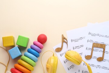 Wooden notes, music sheets, headphones and toys on beige background, flat lay with space for text....
