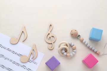 Wooden notes, music sheet and toys on beige background, flat lay with space for text. Baby song...