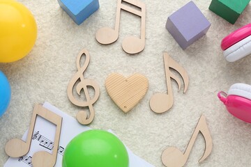 Wooden notes, music sheet and toys on beige textured background, flat lay. Baby song concept