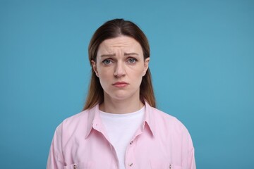 Portrait of sad woman on light blue background