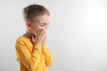 Sick boy with tissue coughing on gray background, space for text. Cold symptoms