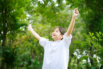 Asian woman breathing clean air in nature forest. Happy girl open arms in happiness. Fresh outdoor...