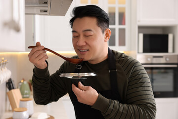 Cooking process. Man tasting dish in kitchen