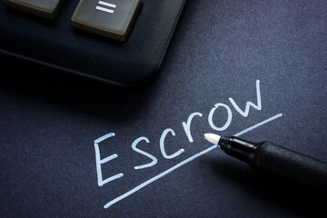 Close-up of a calculator and an inscription Escrow with a marker.