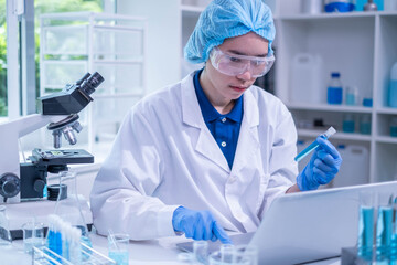 Naklejka premium Closeup female woman scientist's hand holding blue liquid chemical chemistry test tube working in analyze science laboratory research experiment