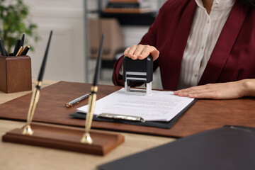Notary stamping document at table in office, closeup - obrazy, fototapety, plakaty