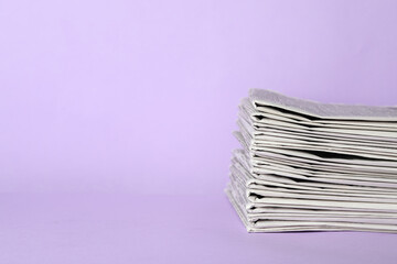 Stack of newspapers on light violet background, space for text. Journalist's work - obrazy, fototapety, plakaty