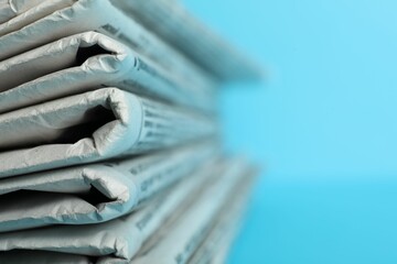 Stack of newspapers on light blue background, closeup with space for text. Journalist's work - obrazy, fototapety, plakaty