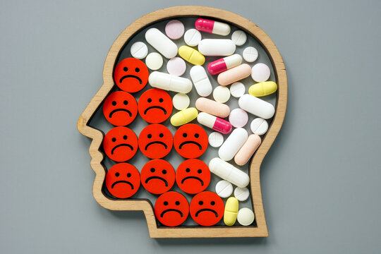 Psychiatric medication for depression. Head, negative emoticons and pills.