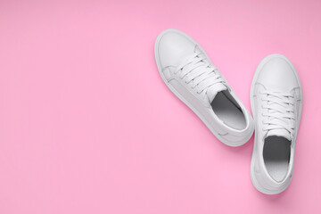 Pair of stylish white sneakers on pink background, top view. Space for text