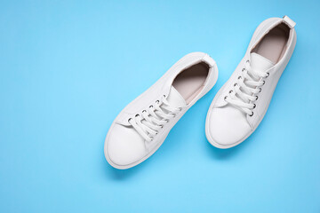 Pair of stylish white sneakers on light blue background, top view. Space for text