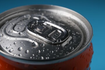 Energy drink in wet can on light blue background, closeup