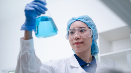 Woman scientist chemist holding laboratory blue liquid beaker test tube equipment for discovery...