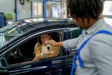 Service completion: African-American mechanic hands car keys to a contented client, embodying...