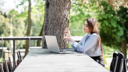 European dissatisfied businesswoman work on laptop computer outdoors. Beautiful young girl sit at...