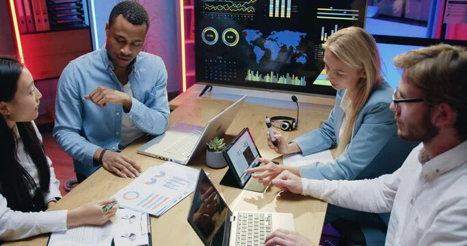 Attractive people man and woman coworkers sitting behind workplace and brainstorming over business strategy in evening office
