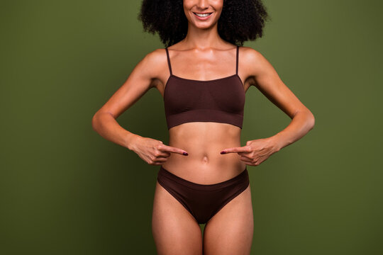 Cropped no filter photo of smiling happy girl showing her tummy healthy diet slimming isolated on khaki color background