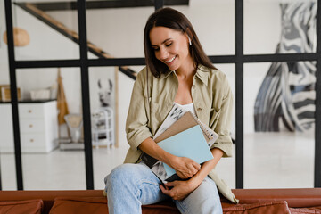 woman sitting on sofa at home relaxed dressed in khaki shirt and jeans