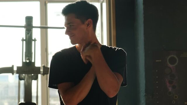 Athletic man warms up hands to avoid traumatization. Man recognizes importance of preventing injuries during upcoming exercises