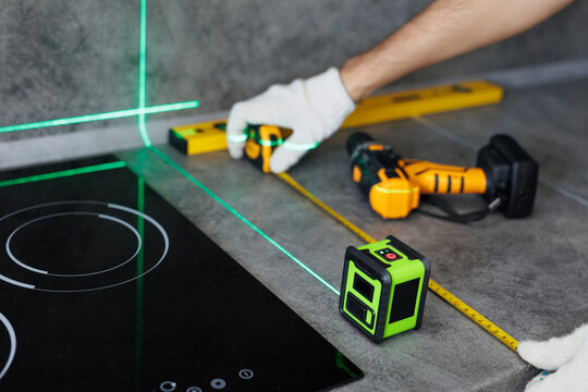 Close-up of hands of a worker who measures the width of a tabletop with a tape measure and a laser.