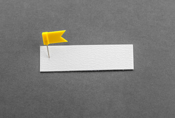 Blank note and yellow thumbtack on a gray background with copy space. Overcoming the barriers....