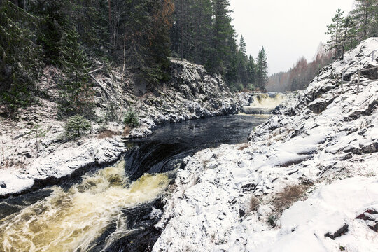 Snowy cascade waterfall. Landscape photo of Kivach Falls on a cold cloudy winter day