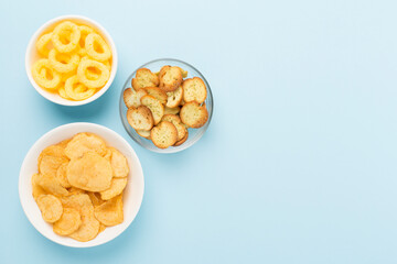 Various unhealthy snacks on color background, top view