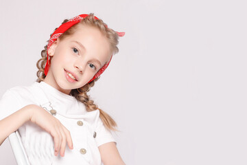 Expressive poses! Little girl with light brown hair showcases emotions while standing and sitting on a chair against a white wall.