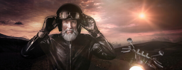 Portrait d'un motard biker homme avec un casque noir et une veste en cuir et des lunettes de protection et une barbe grise vintage