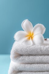Fototapeta na wymiar Frangipani flower on stack of white towels, a close-up of a delicate, pink plumeria flower with soft petals, on a white, textured surface.