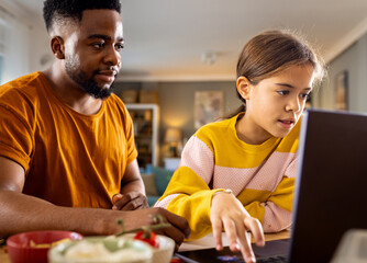 Young father helping his daughter with her homework at home in living room.