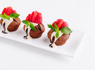 Cupcakes with strawberries on white plate