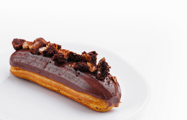 Eclair with Chocolate Cream and Hazelnuts on White Plate