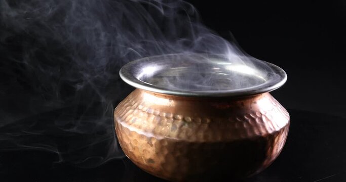 Brass copper metal Indian style pot Smoke vape fog rising flowing moving rotate on black background
