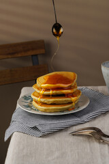 A stack of pancakes with honey on a vintage plate on the table. Breakfast.