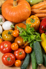Сlose-up shot of various fresh vegetables, displaying a rich array of colors and textures. There’s an assortment of leafy greens and herbs interspersed among the other vegetables