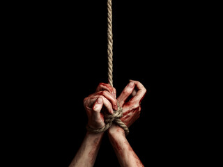 Hostage woman hands with bloody stains tied with a rope over black background