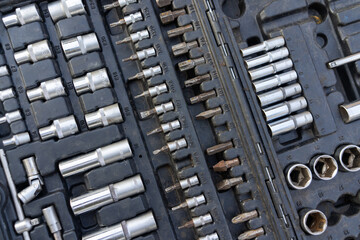 Close-up view of a well-organized toolbox containing various sizes of sockets, socket wrenches, and other related tools. The tools are metallic and show signs of use. 