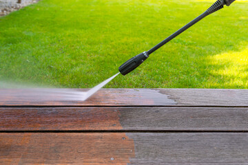 cleaning terrace with a power washer - high water pressure cleaner on wooden terrace surface - shallow depth of field - 740065071