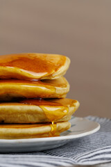 A stack of pancakes with honey on a vintage plate on the table. Breakfast.