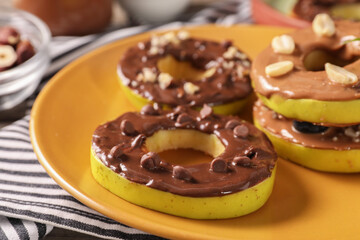 Fresh apples with nut butters, peanuts and chocolate chips on table, closeup