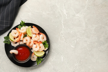 Tasty boiled shrimps with cocktail sauce, parsley and lime on light grey table, top view. Space for text