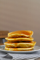 A stack of pancakes with honey on a vintage plate on the table. Breakfast.