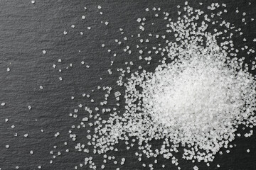 Heap of granulated sugar on black table, top view. Space for text