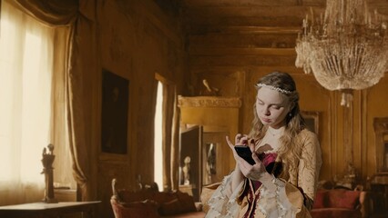 Woman in ancient outfit on background of historic interior. Female in renaissance style dress...