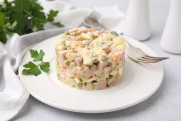  Tasty Olivier salad with boiled sausage and fork on light table © New Africa
