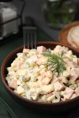 Tasty Olivier salad with boiled sausage in bowl on table, closeup