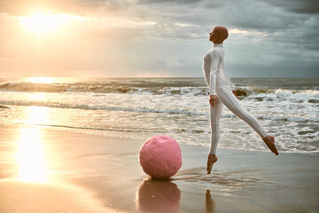 Hairless ballerina with alopecia in white futuristic suit jumps next to pink sphere and soaring...