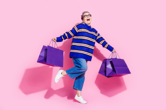 Full body photo of attractive pensioner woman hold shopping bag have fun wear trendy blue striped clothes isolated on pink color background