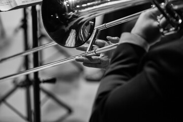 A fragment of a trombone in the hands of a musician close-up in black and white